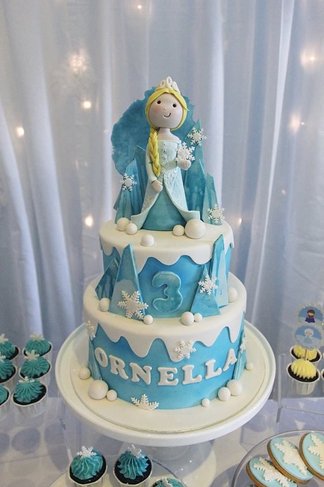 A gorgeous two-tiered Frozen cake decorated with white chocolate shards painted with edible blue paint, fondant snowballs and snowflakes cutouts.. Little House of Dreams. Source