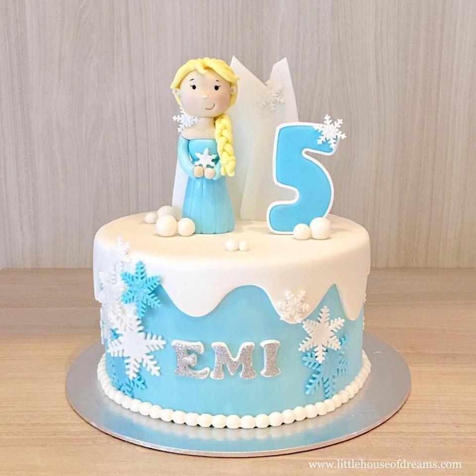 An Elsa cake topper with snowflakes and snowballs instantly transform a regular round cake into a Frozen themed cake. Little House of Dreams. Source