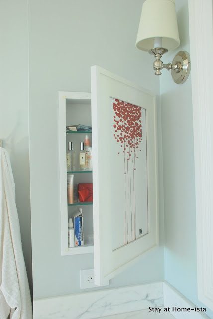 Recessed cosmetics cabinet hidden behind artwork