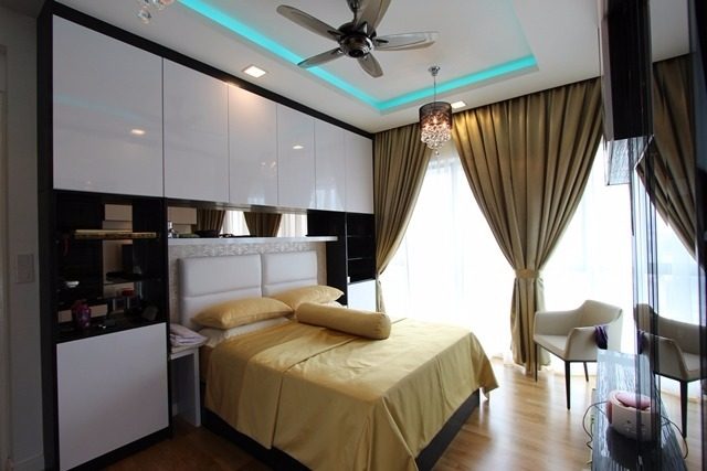 In this bedroom in Setia Sky by Ark Studio, ceiling-height storage is built around the head of the bed. Floating drawers were also added on the opposite wall deep enough for a TV.