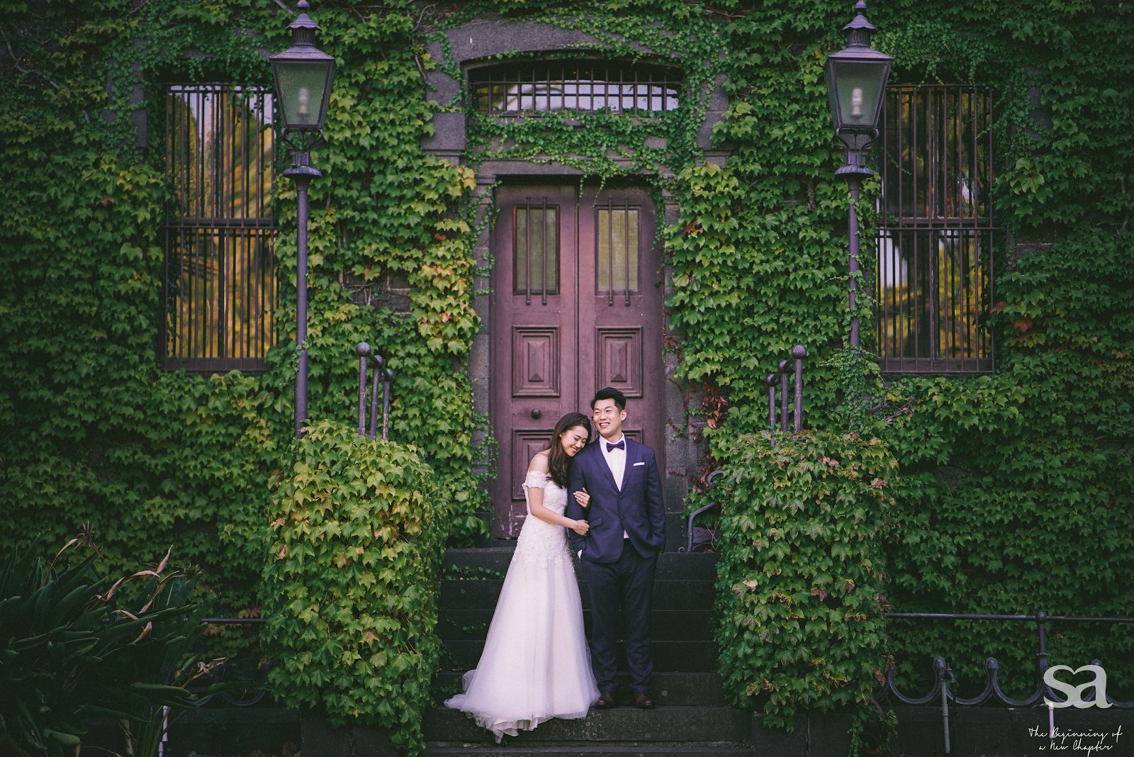 Malaysian wedding couple poses in front of a green covered wall. Photo by SA Photography