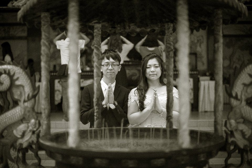 Wedding couple prays for blessings at Thean Hou Temple Kuala Lumpur. Photo by J Seven Studios. Hire wedding photographers at Recommend.my