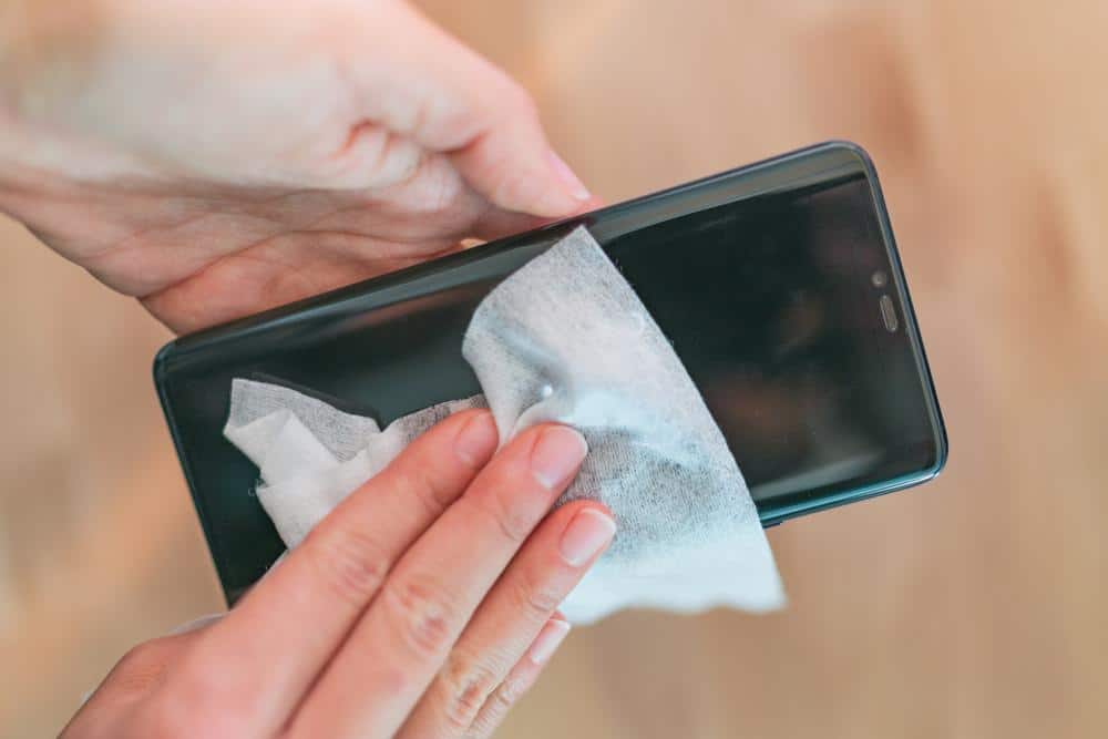 Wiping smartphones with disinfectant wipes