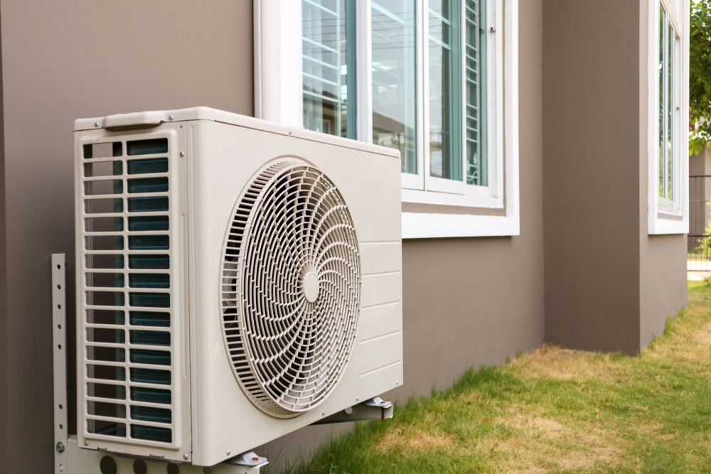 Air conditioner compressor in an open area next to the house