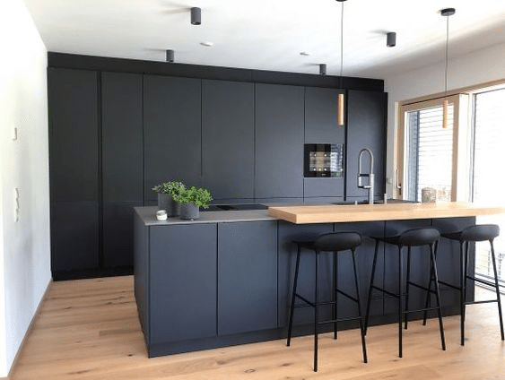 Scandinavian-styled black kitchen cabinetry with a light wood bar counter