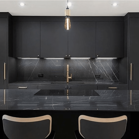 Black kitchen cabinetry with gold cabinet door handles and sink fixtures