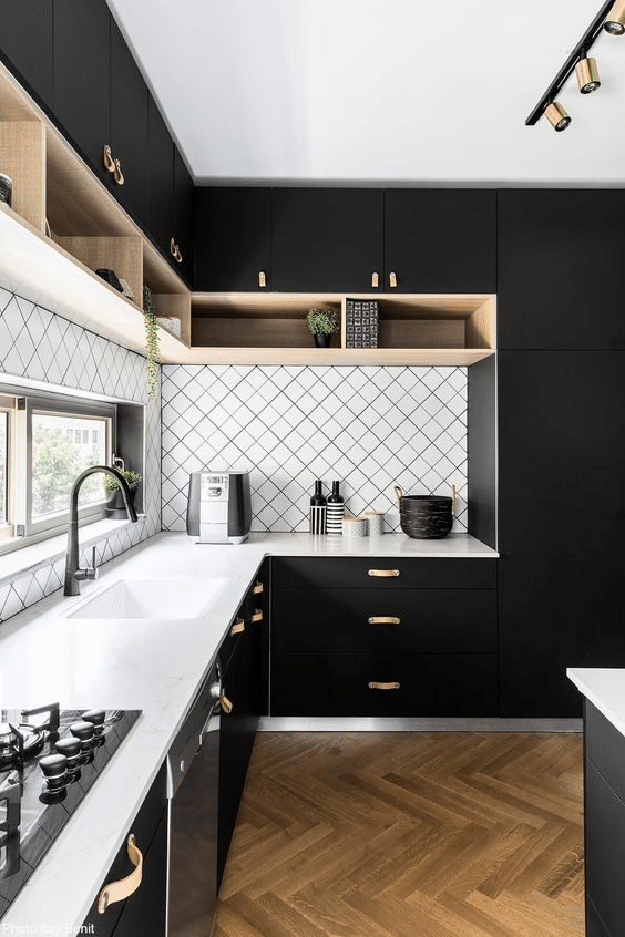 Black kitchen cabinetry with leather door handles and light toned accents 