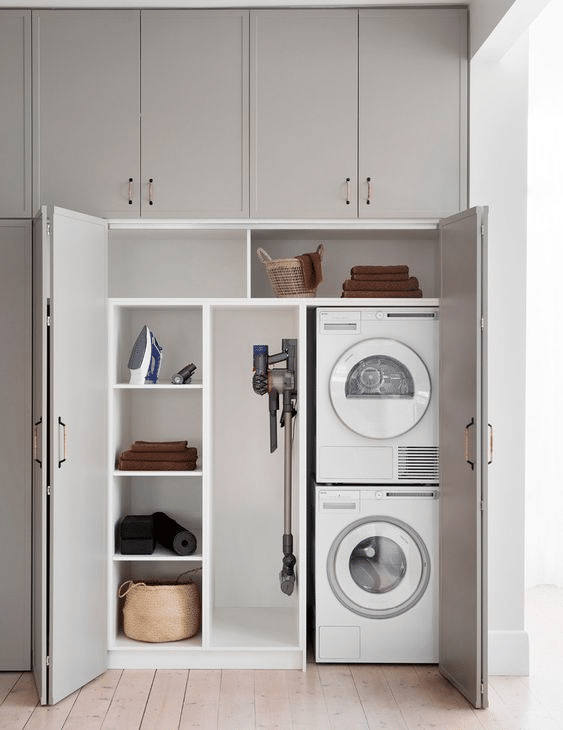Hidden laundry area inside built-in cabinetry with exposed shelves