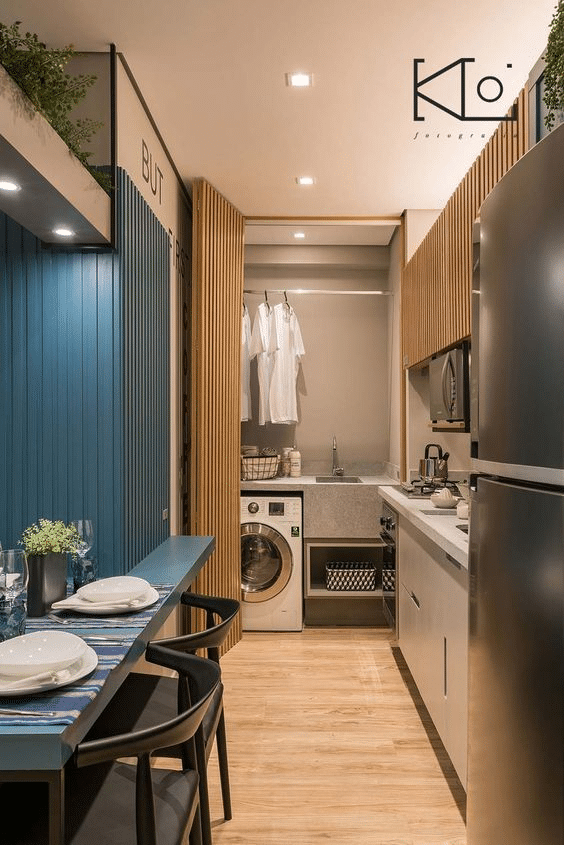 Hidden laundry nook in studio apartment kitchenette with wooden panel bifold door